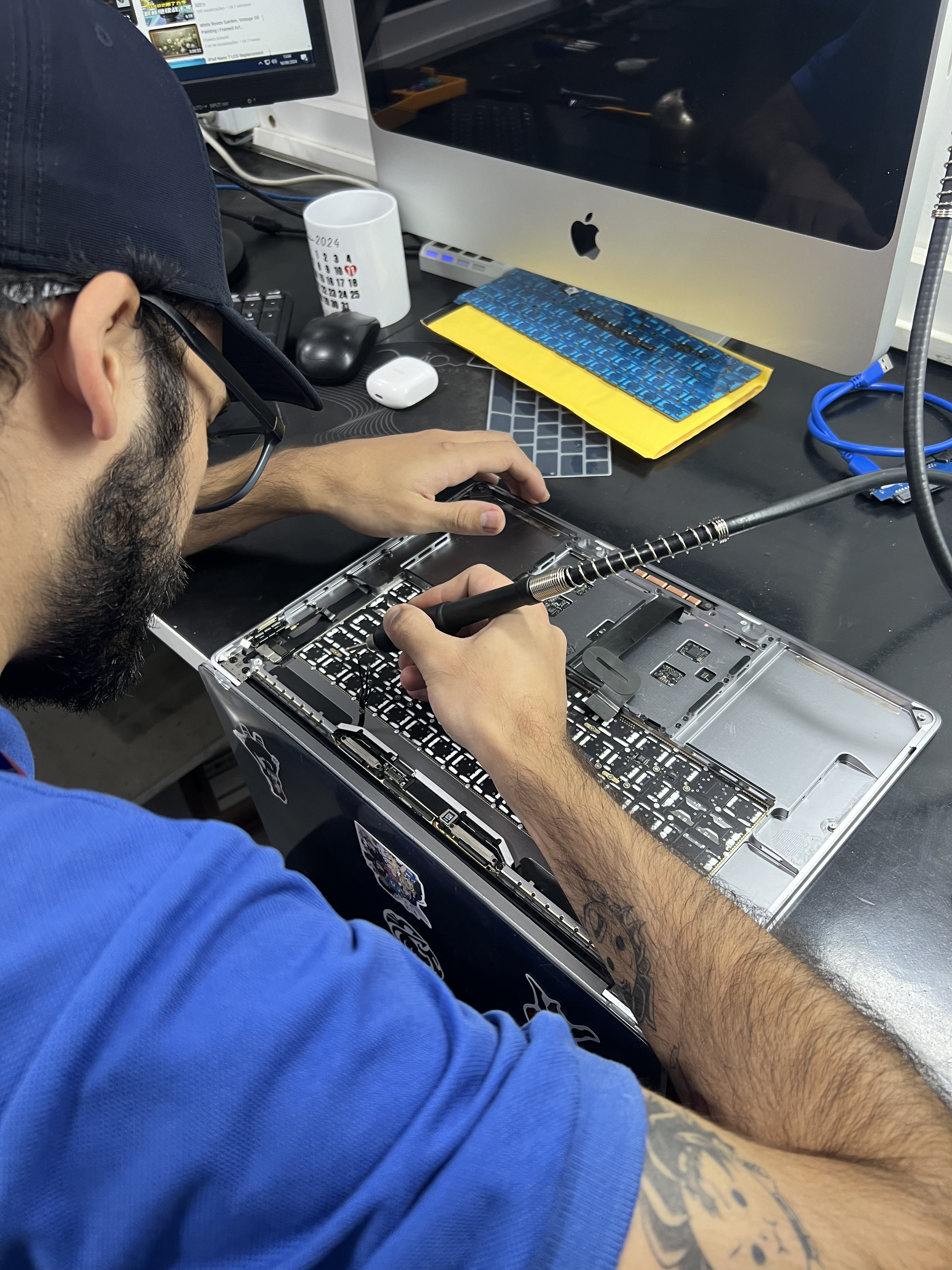 Técnico da VirABC realizando reparo eletrônico em um MacBook